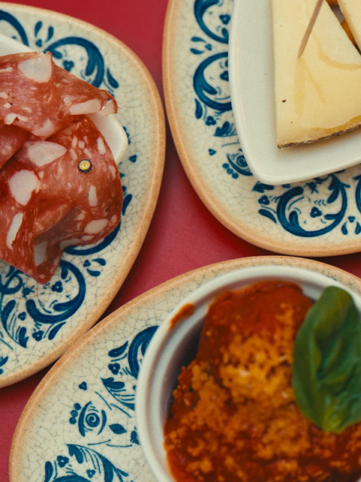 Toskanische Antipasti auf blau-weißen Keramiktellern: Salami, Pecorino und Polpettine in Tomatensoße