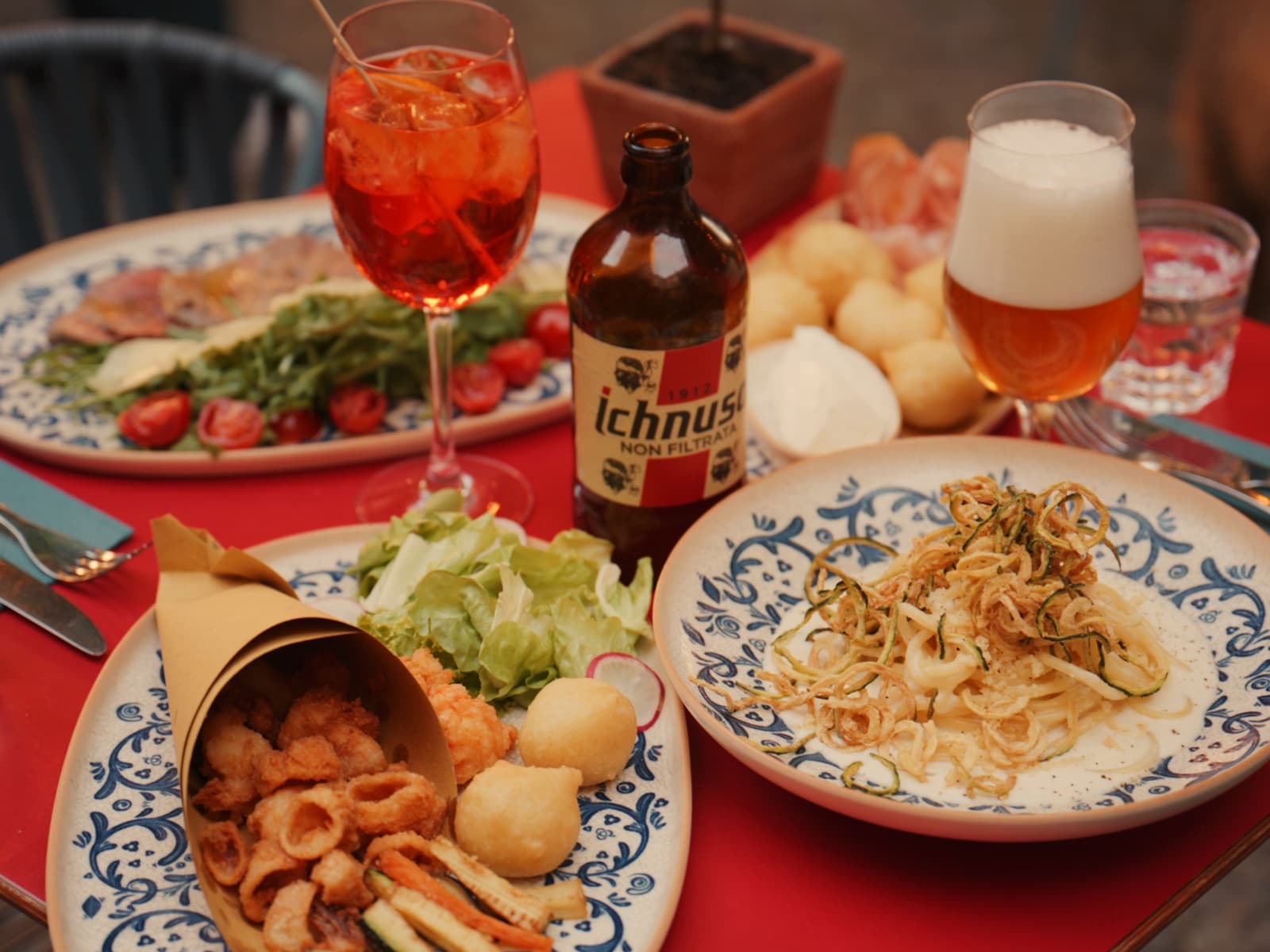 Gedeckter Tisch mit Fritto misto, Pasta, Coccoli, Aperol Spritz und Bier