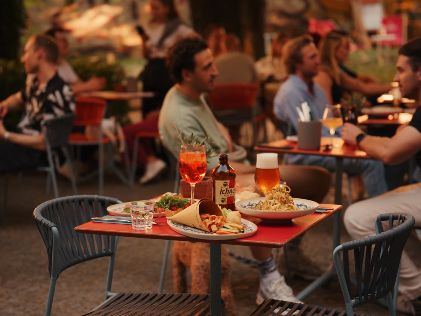 Gäste auf der Terrasse der Rustikeria, im Vordergrund ein gedeckter Tisch mit Pasta, Fritto und Aperitivo