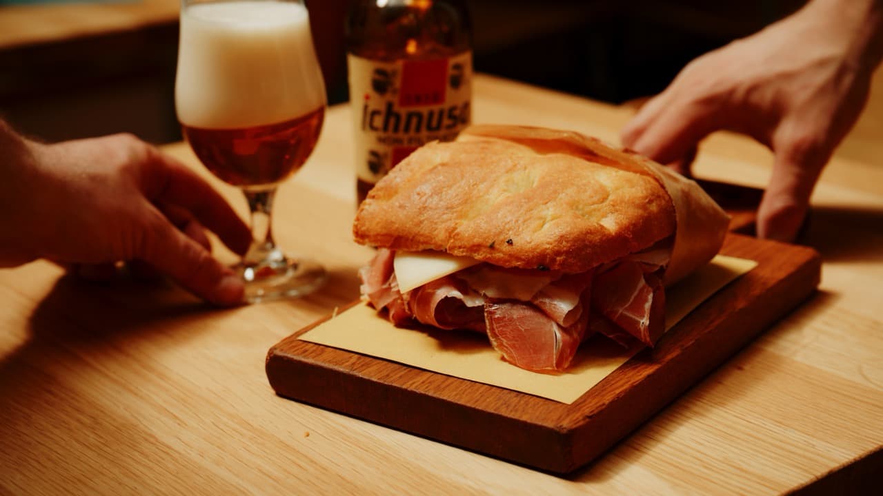 Schiacciata mit Prosciutto crudo auf einem Holzbrett, dazu ein Bier